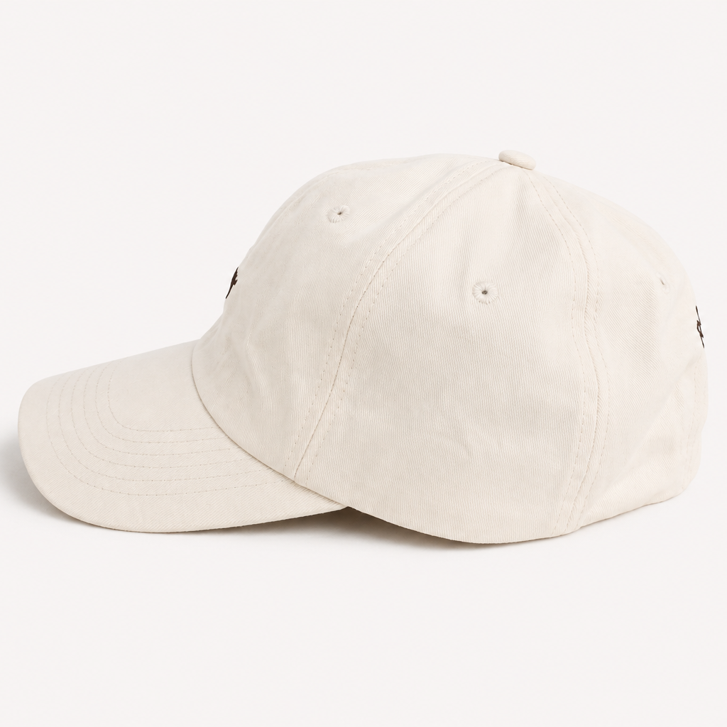 An off-white cotton baseball cap shown from a three-quarters angle on a clean, solid off-white background.